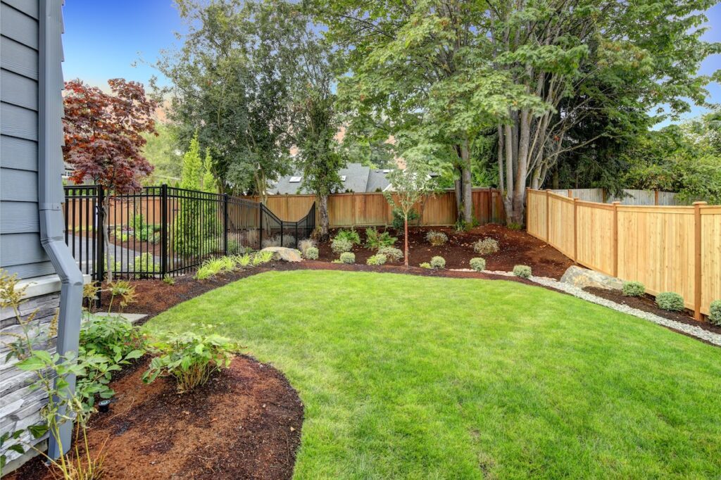 View of an attractive backyard with new planting beds and well kept lawn