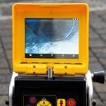 A drain cleaning company checks a blocked drain with a camera before flushing it out. Screen shows the cleaning process of the blocked pipe.