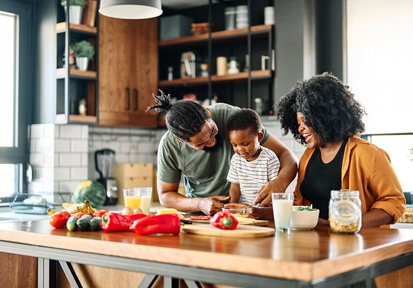 Portrait of mother, father and son preparing and eating breakfast in the kitchen at home
