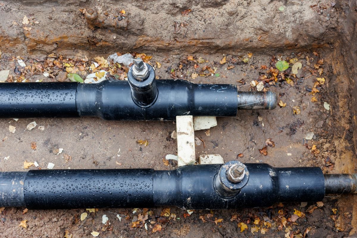 New modern insulated urban pipeline installation construction site exposed underground pipes in shored trenches