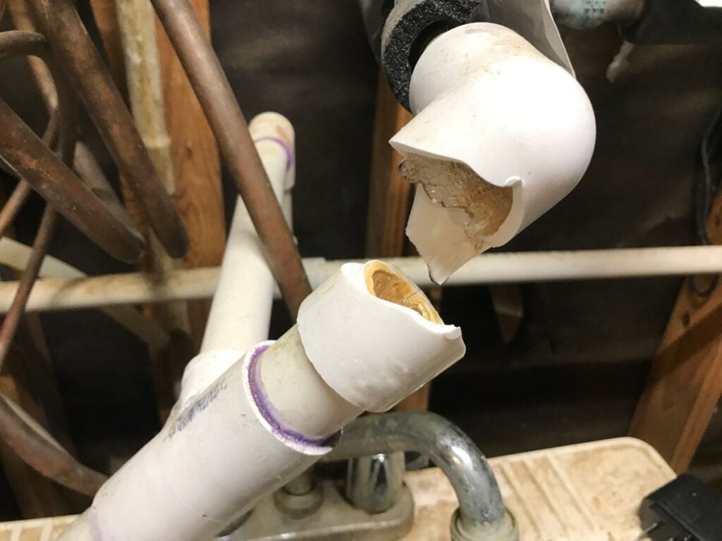 Busted plumbing PVC water pipe with ice frozen and water dripping