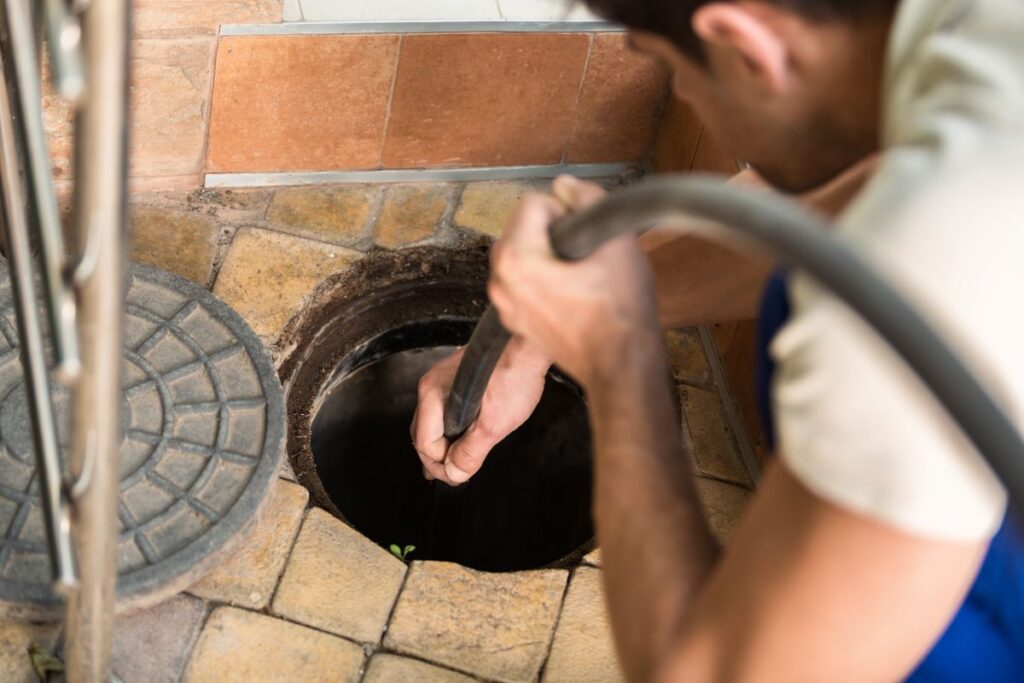 Worker performs the installation of pumping equipment. Sewer cleaning.