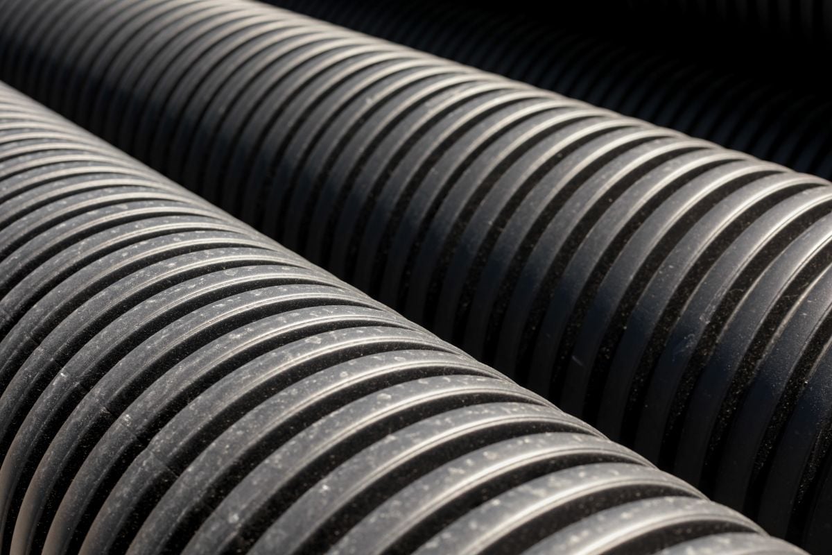Rows of black corrugated plastic drainage pipes stacked together