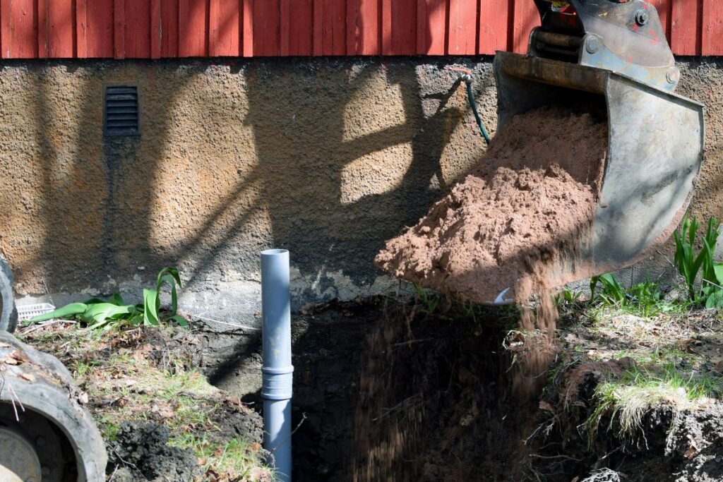 Excavator in construction site filling the sewer pipe
