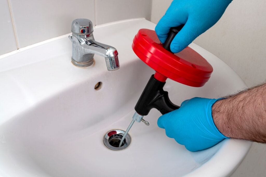 Plumbing issues, occupation in sanitation and handyman contractor concept with plumber repairing drain with plumbers snake