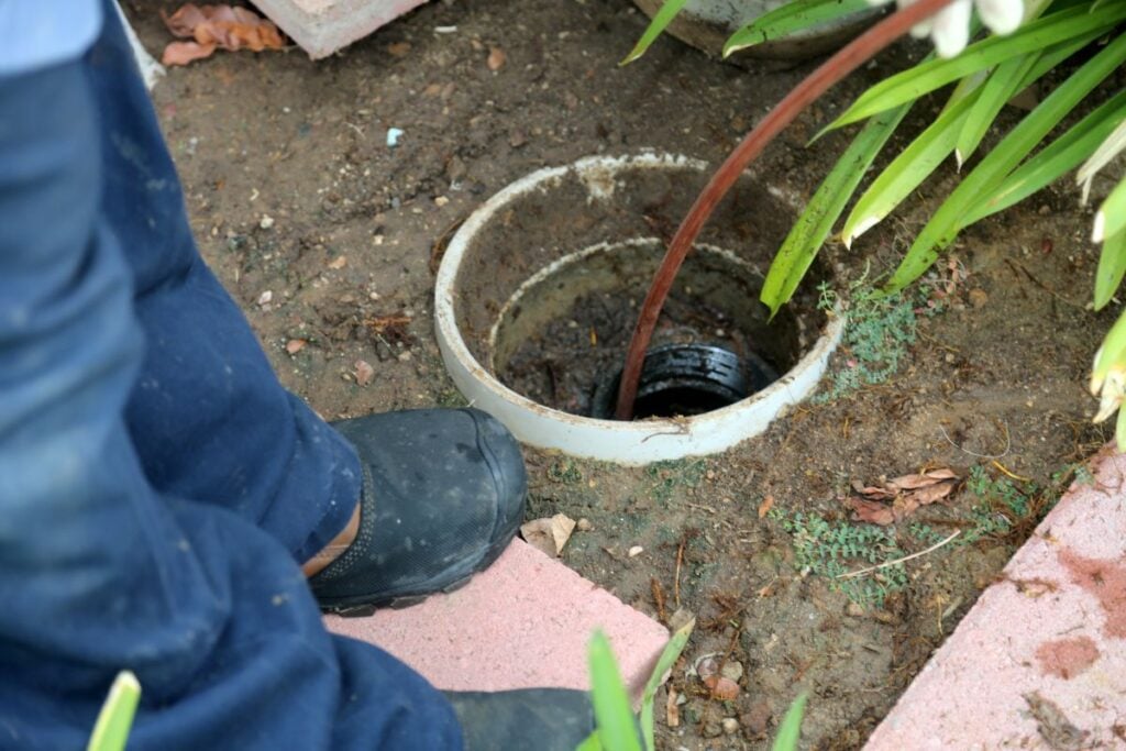 Sewer cleaning. A plumber uses a sewer snake to clean blockage in a sewer line
