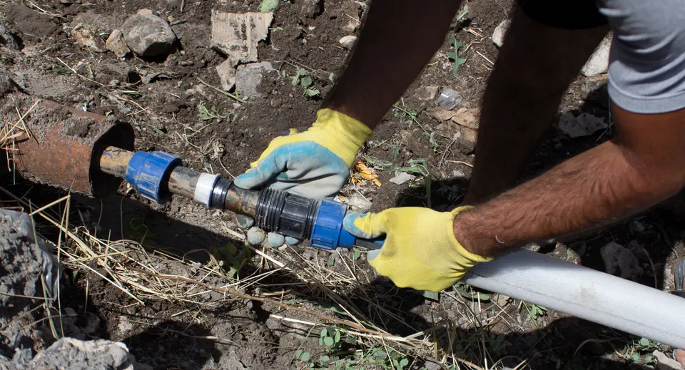 Plumber connects a water pipe in a trench